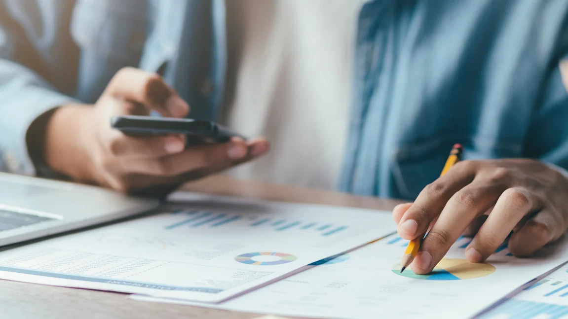 Un homme travaille au bureau avec un téléphone et un crayon dans la main